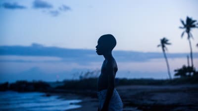 Chiron (Alex R. Hibbert) står på en sandstrand och tittar ut över havet.