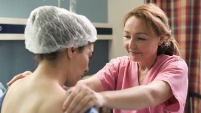 Claire håller händerna lugnande på en patients axlar.