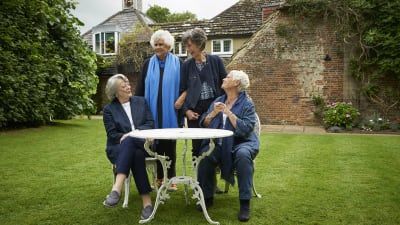 Fyra glada damer i samspråk i  Joan Plowrights trädgård.