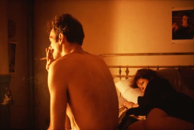 Nan Goldin ligger på sängen och ser på Brian som sitter på sängkanten och röker.