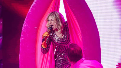Kvinna i glittriga kläder sjunger i mikrofon 