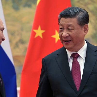 Venäjän Putin ja Kiinan Xi keskustelevat, maiden liput taustalla. 