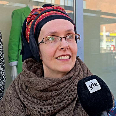 Leenu Sammeta seisoo vaatekaupan näyteikkunan edessä.
