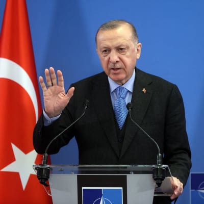 Turkiets president Erdogan - i bakgrunden Natos och Turkiets flaggor