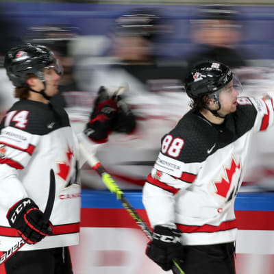 Två kanadensiska spelare skrinnar förbi spelarbåset och firar ett mål.