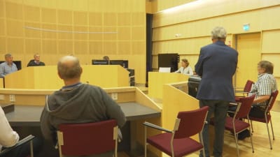 Bild inne från rättsalen. De åtalade i M/S Mässkär-rättegången sitter ner. Domare , nämdemän och åklagaren syns också.