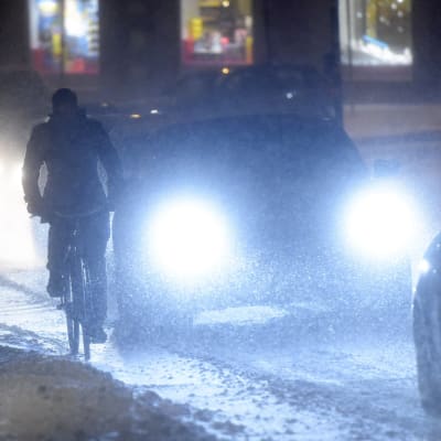 En cyklist och bilar i snöstorm. 