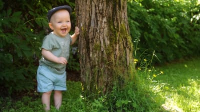Oliver på sin 1-årsdag. Står vid ett träd. 