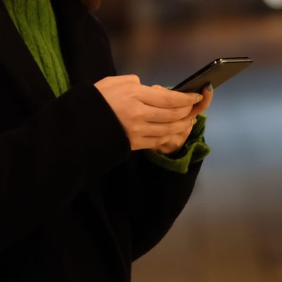Kvinna håller en mobiltelefon i handen.