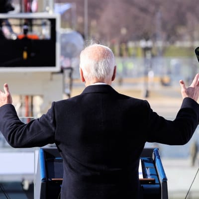 Joe Biden fotad bakifrån när han håller sitt tal under presidentinstallationen. Han håller upp båda händerna.