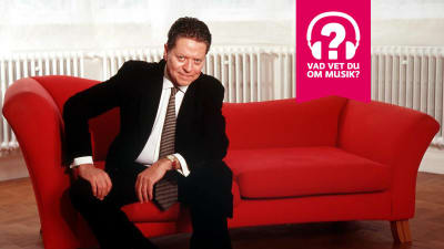 Robert Palmer sitter på en soffa.