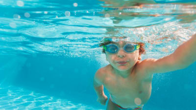 En pojke som simmar med simglasögon på