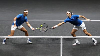 Nadal och Federer på samma sida nätet, kämpar om bollen