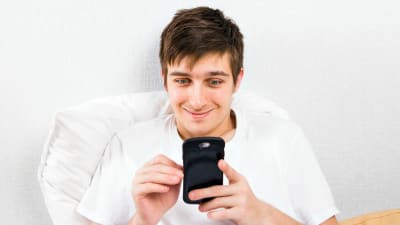 En kille underhåller sig genom att titta på sin telefon.