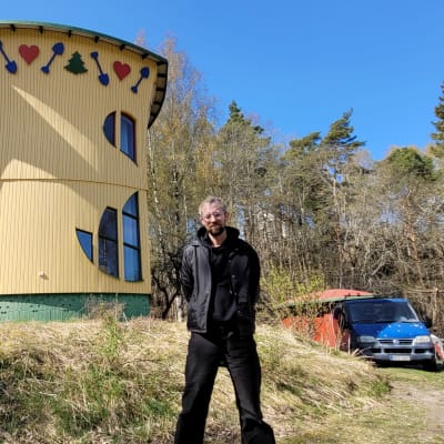 Man i svart rock utanför ett hus.