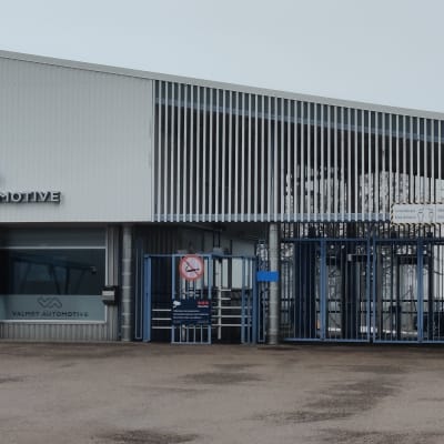 Sininen tehtaan portti. Seinässä lukee "Valmet Automotive".