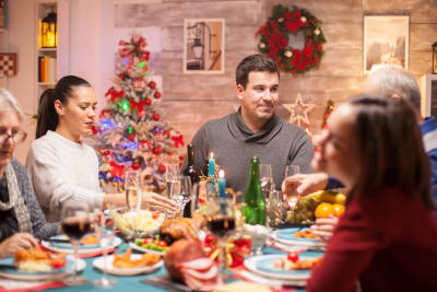 Människor sitter runt ett julbord och äter mat. Julfirande