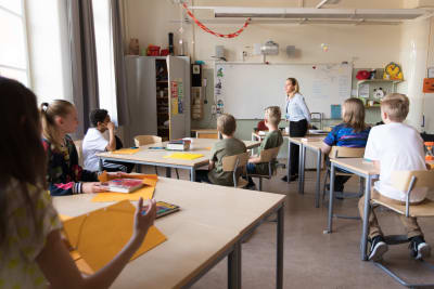 Elever i en skolklass sitter och lyssnar på läraren.