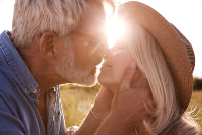 Man och kvinna kysser varandra i solnedgång