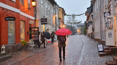 En person med rött paraply går på ågatan i Borgå.