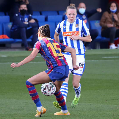 Sanni Franssi i vitblå speltröja spelar bollen mot en Barcelonaspelare i rödblå tröja.
