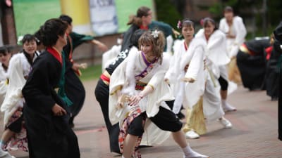 Flera personer iklädda antingen svarta eller vita dräkter. De dansar en japansk dans kallad yosakoi.
