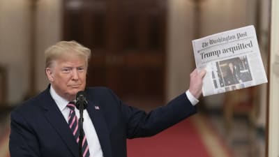 Donald Trump visar upp en tidning med rubriken "Trump aquitted", det vill säga Trump frikänd.