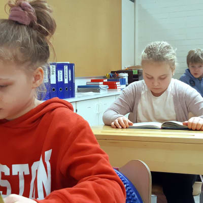 Skolelever läser i ett klassrum. 