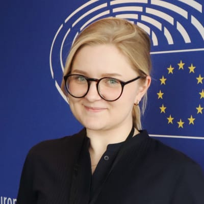 Bild på Marie Krogius som praktikant vid Europaparlamentet med EU:s flagga i bakgrunden 