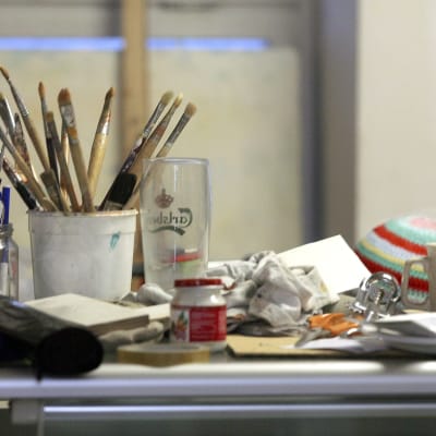 En konstnärs penslar och andra saker står på ett bord