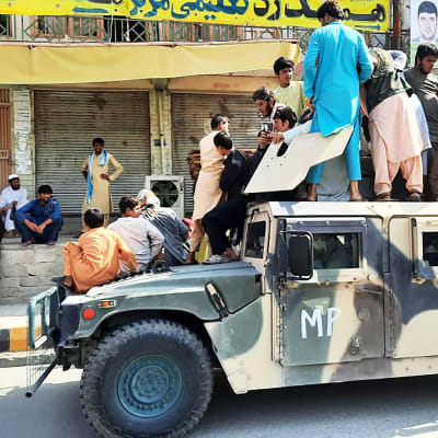 Paikallisia siviilejä ja taliban-taistelijoita Afganistanin armeijan hylkäämän Humvee-ajoneuvon päällä Laghmanissa