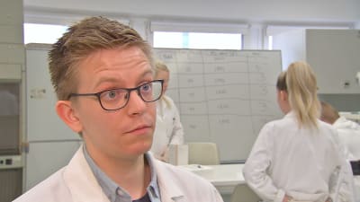 Jakob Storbacka, en ung man med glasögon och laboratorierock, i ett laboratorium.