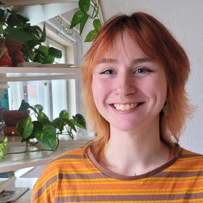 Kvinna med orange skjorta och rött hår.