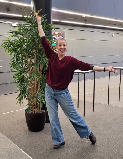 en glad kvinna jeans gör en danspose och ler mot kameran