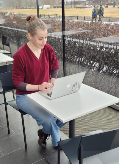 en kvinna sitter på ett cafe och skriver på sin laptopt