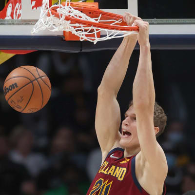 Lauri Markkanen i vinröd spelblus hänger kvar i korgen efter en dunk.