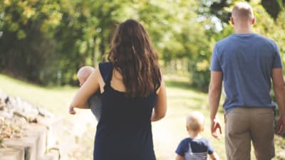 Mamma, pappa och två barn promenerar i en park.