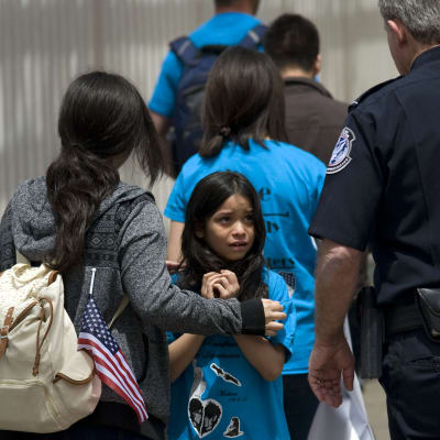 En flicka tittar skrämd upp mot en gränspolis.