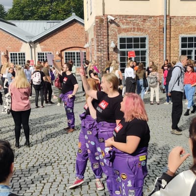 En innergård full med studerande, några med lila halare.