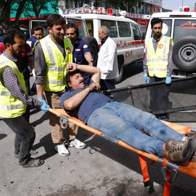 En skadad man bärs iväg på bår efter självmordsattacker i Afghanistans huvudstad Kabul. 