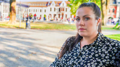 Kaisa Augusta Hansén-Suckow sitter på en parkbänk i solen och tittar in i kameran.
