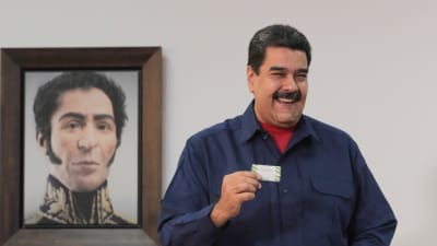 Nicolás Maduro lägger sin röst i söndagens lokalval, med ett porträtt på nationalhjälten Simón Bolívar i bakgrunden. 