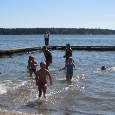Simskolebarn som springer upp ur vattnet