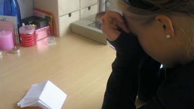 En flicka som lutar huvudet i handen