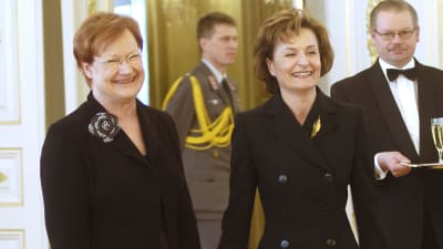 Tarja Halonen håller Anneli Jäätteenmäki i handen och båda ler.