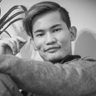 En svartvit bild av Nathanael Taher Ahmady. Han ler och ser in i kameran