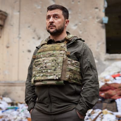 Ukrainas president Volodymyr Zelenskyj står bland ruiner med en allvarlig min.