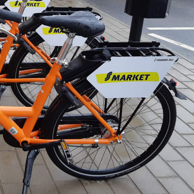 Flera orange stadscyklar på rad som folk kan hyra.