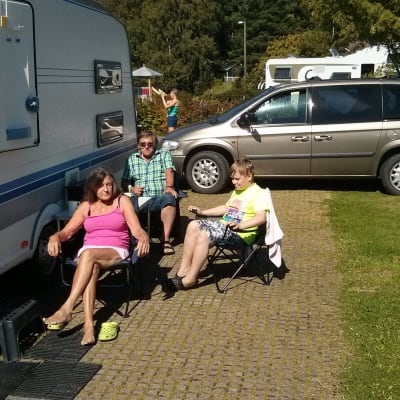 Lilja tekoniemi med familj sitter utanför sin husvagn på Rastböle campingområde