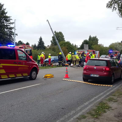 Räddningsmanskap på plats vid en trafikolycka där en bil kört in i en lyktstolpe.